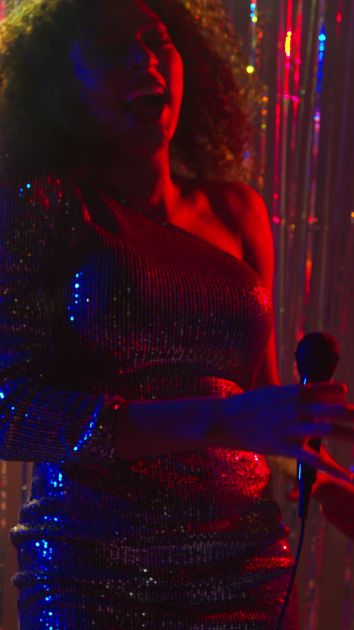 video vertical de una mujer joven con micrófono cantando en un bar de karaoke o discoteca con luces brillantes en el fondo