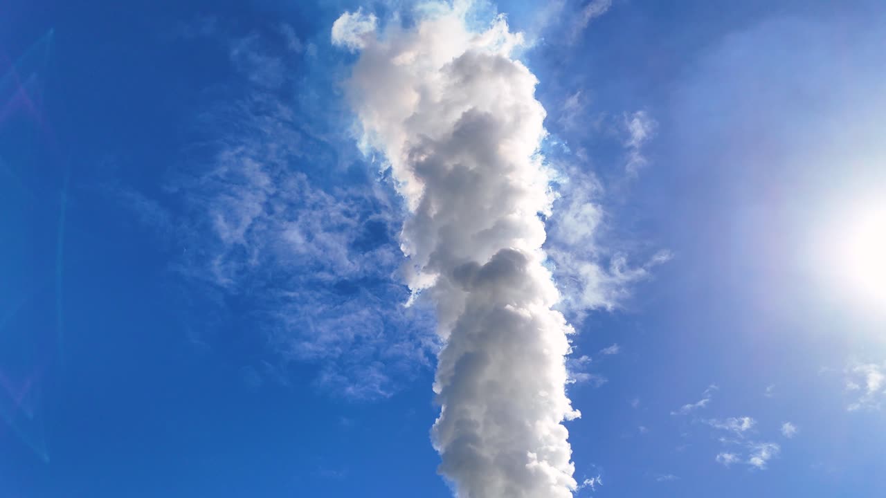 Thick smoke rises from a chimney into a bright blue sky, highlighting environmental concerns and air pollution