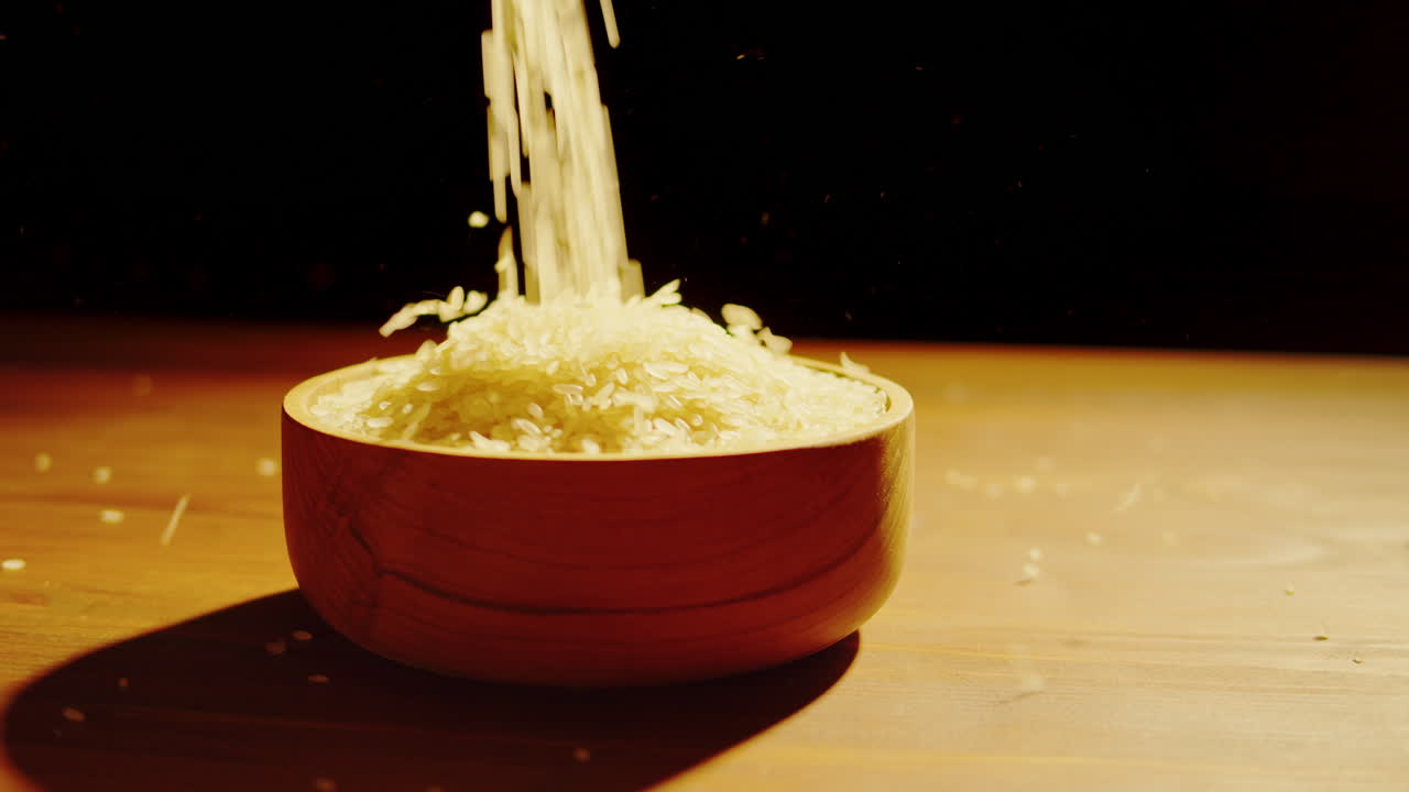 Rice Grains Pouring into a Wooden Bowl