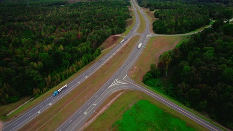 Aerial-follow-perspective-of-Semi-truck-driving-on-interstate-in-a-densely-forested-area