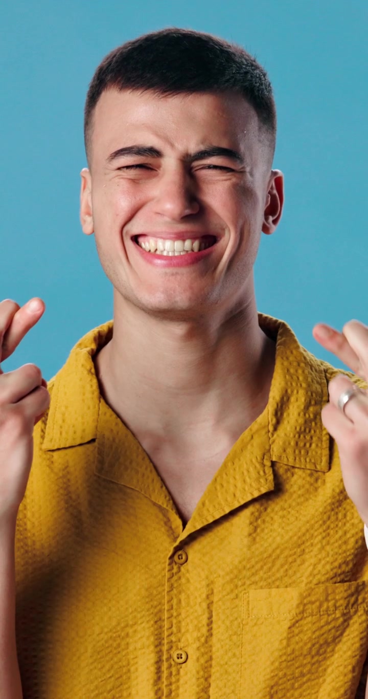 Giovane uomo che incrocia le dita e sorride in studio