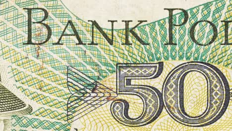 close-up pan across a polish zloty note, revealing “bank polski” lettering and the 50 mark
