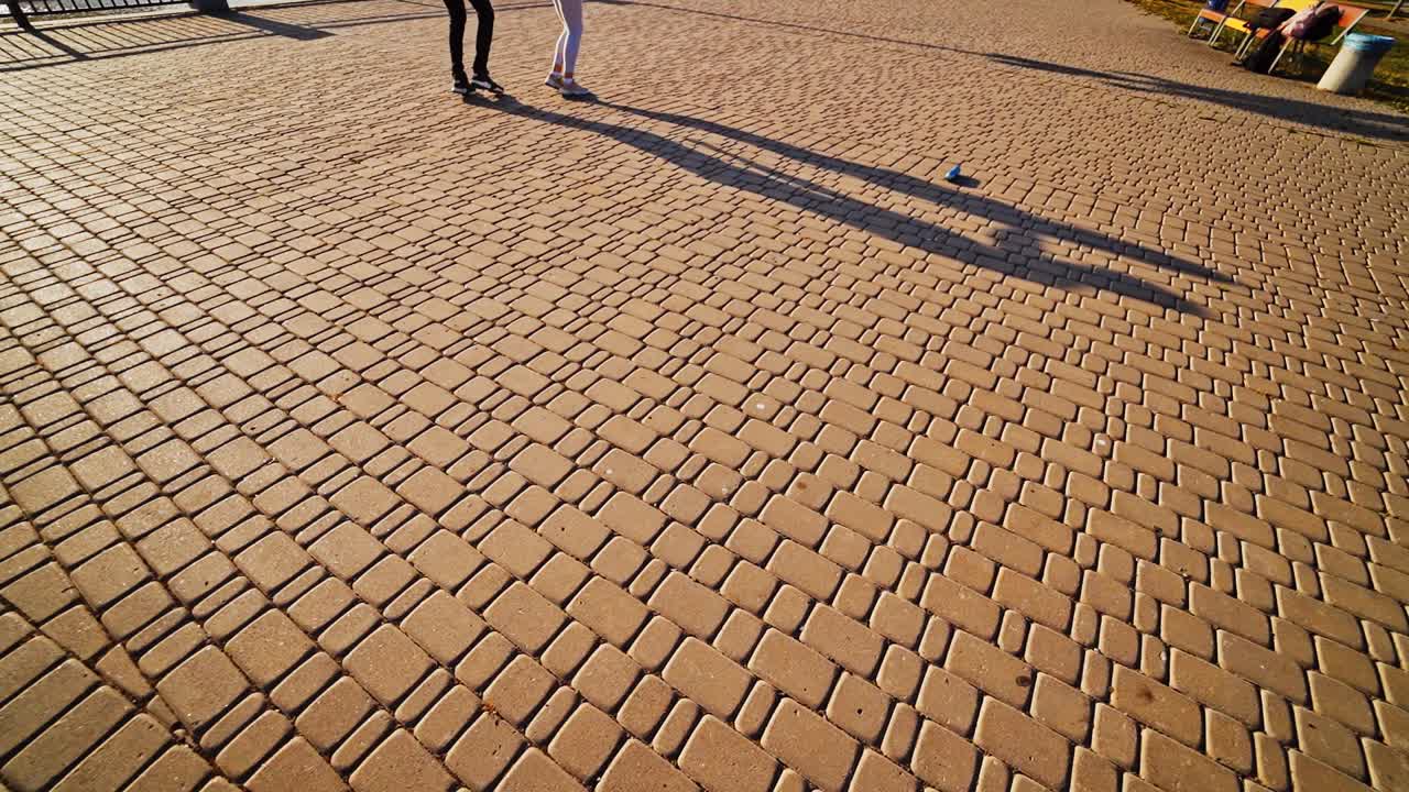 Modern dancers are dancing in the street. Urban lifestyle. Hip-hop generation. Boy's and girl's legs on the video. Paving stones and shades at sunset.