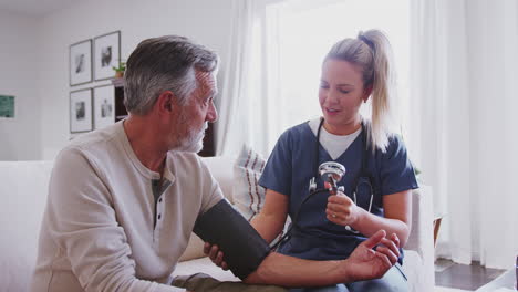 female healthcare worker taking the blood pressure of a senior man during a home health visit