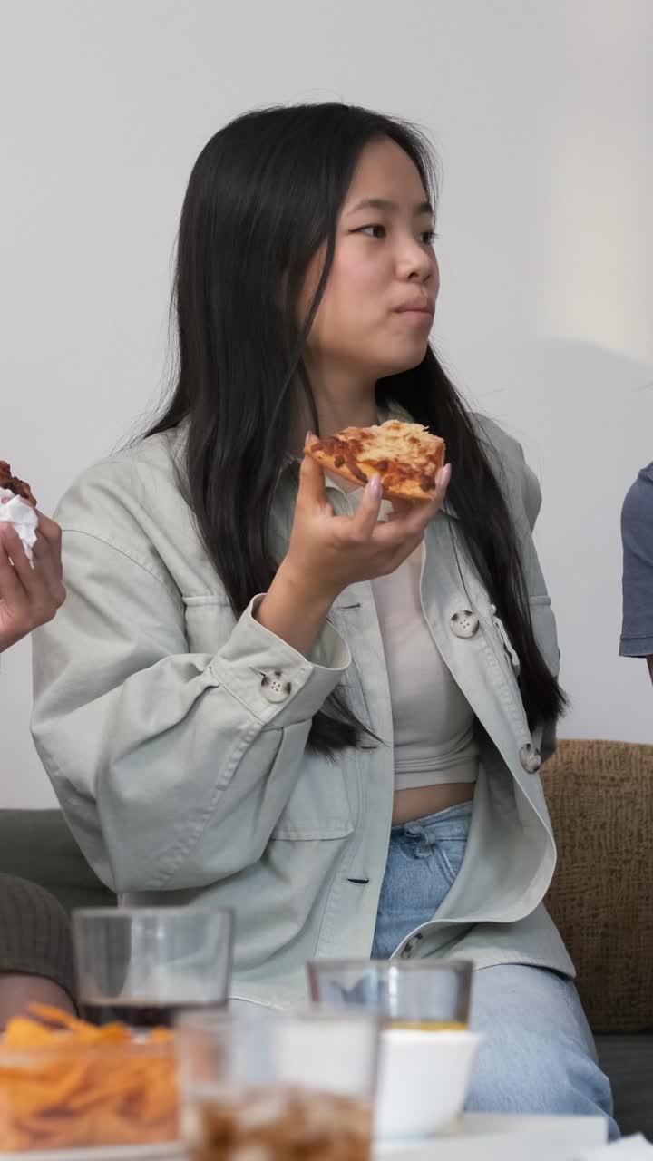 Diverse friends cheering up for woman bringing pizzas during weekend party at home