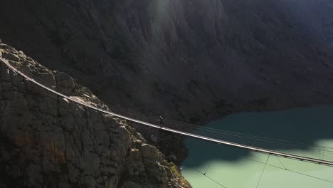 circling shot tracking a single person walking alone over the long and narrow suspension bridge