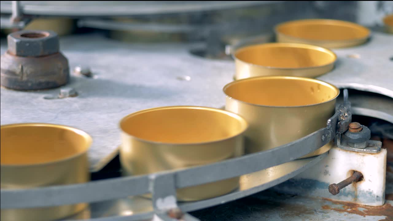 금색 아연 캔이 컨베이어 벨트를 따라 들어오고 있습니다.