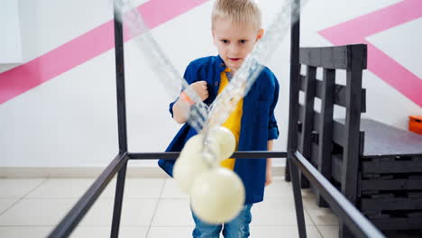 boy makes an experiment with newton's pendulum. the concept of physics. museum of science