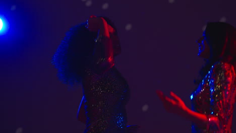 cerca de dos mujeres en un bar de discoteca o discoteca bailando con confeti dorado cayendo 2