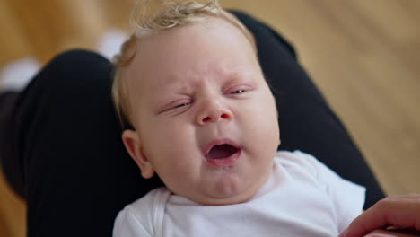 adorable tiny caucasian baby yawning sweetly. close up. mom's touches little kid's nose.