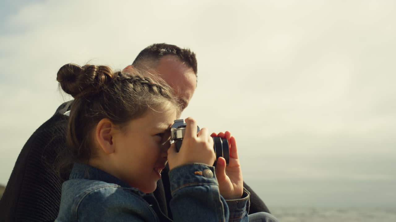 niño dulce tomando fotos en la playa. niña pequeña sostener cámara de fotos en un viaje familiar