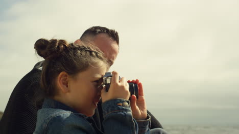 sweet child taking photos on beach. little girl hold photo camera on family trip