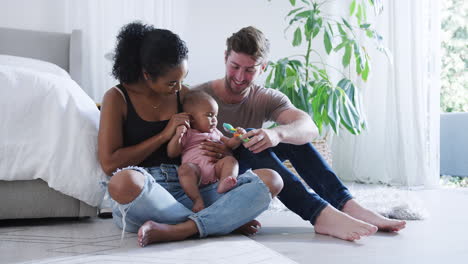 Liebevolle-Eltern-Spielen-Mit-Ihrer-Kleinen-Tochter,-Die-Im-Schlafzimmer-Auf-Dem-Boden-Sitzt