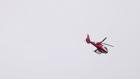 a red helicopter flies over a cloudy sky near the twelve apostles, showcasing aerial views of port campbell, victoria