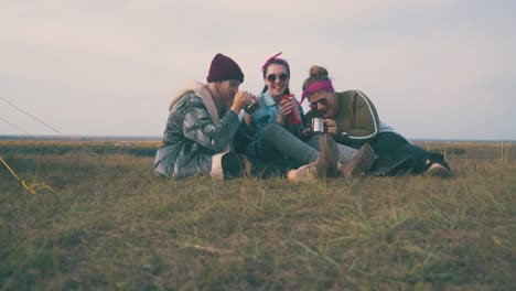 Junge-Frauen-Ruhen-Sich-Mit-Getränken-Auf-Grünem-Gras-Im-Zelt-Aus