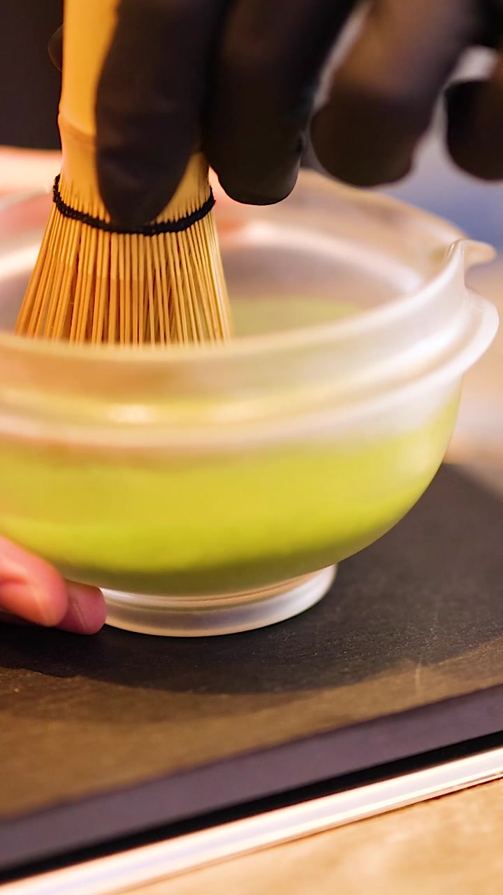 Primo piano della preparazione del tè verde Matcha con un Chasen tradizionale in bambù