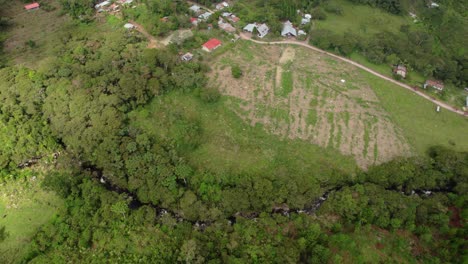 Drone orbital aerial view of green field and hills with pine trees a cloudy day in Oxapampa, Peru.