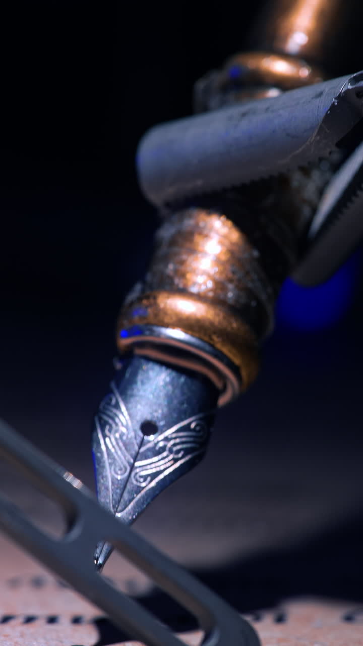 Tiny forceps of robotic arm hold the old-fashioned writing pen. Close up. Da Vinci performs writing in dark surgical room. Vertical video