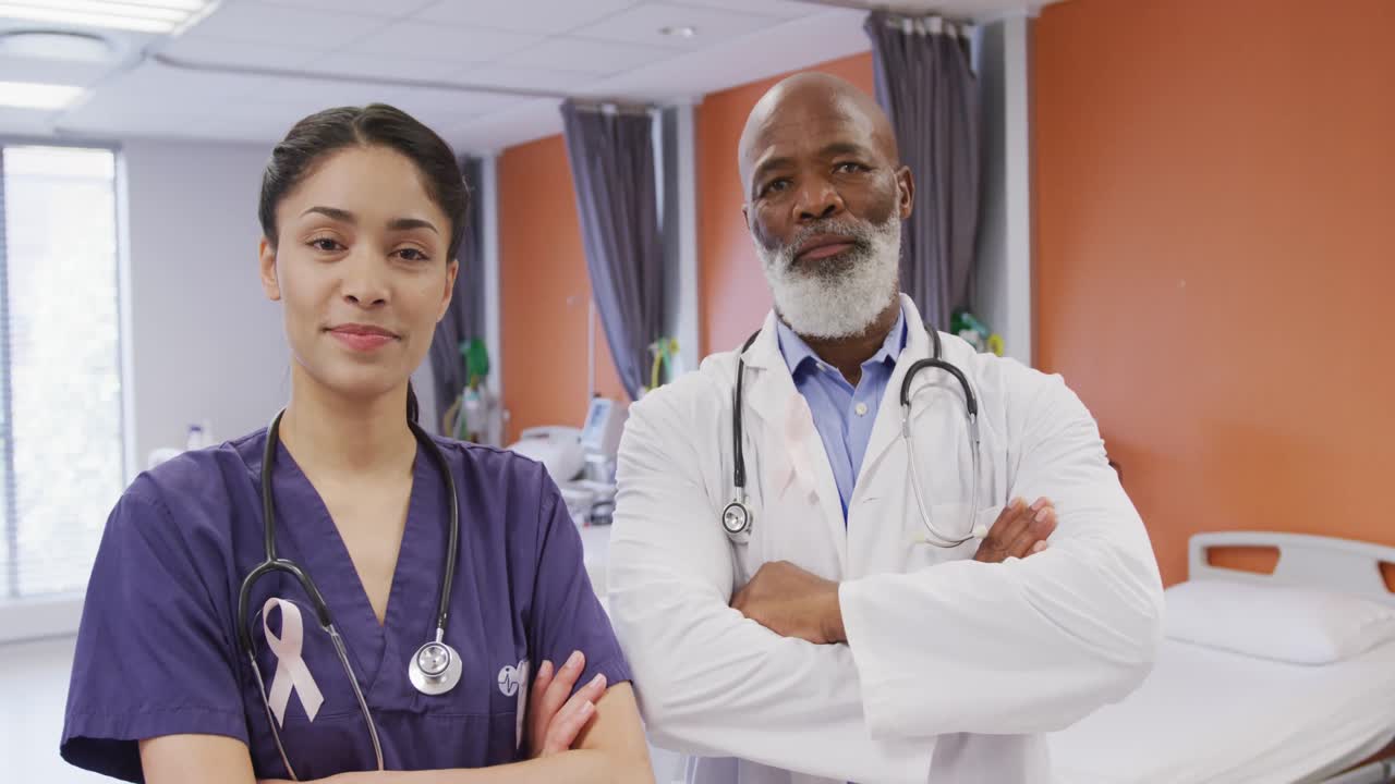 Portrait of smiling diverse male and female doctors wearing cancer awareness ribbons at hospital