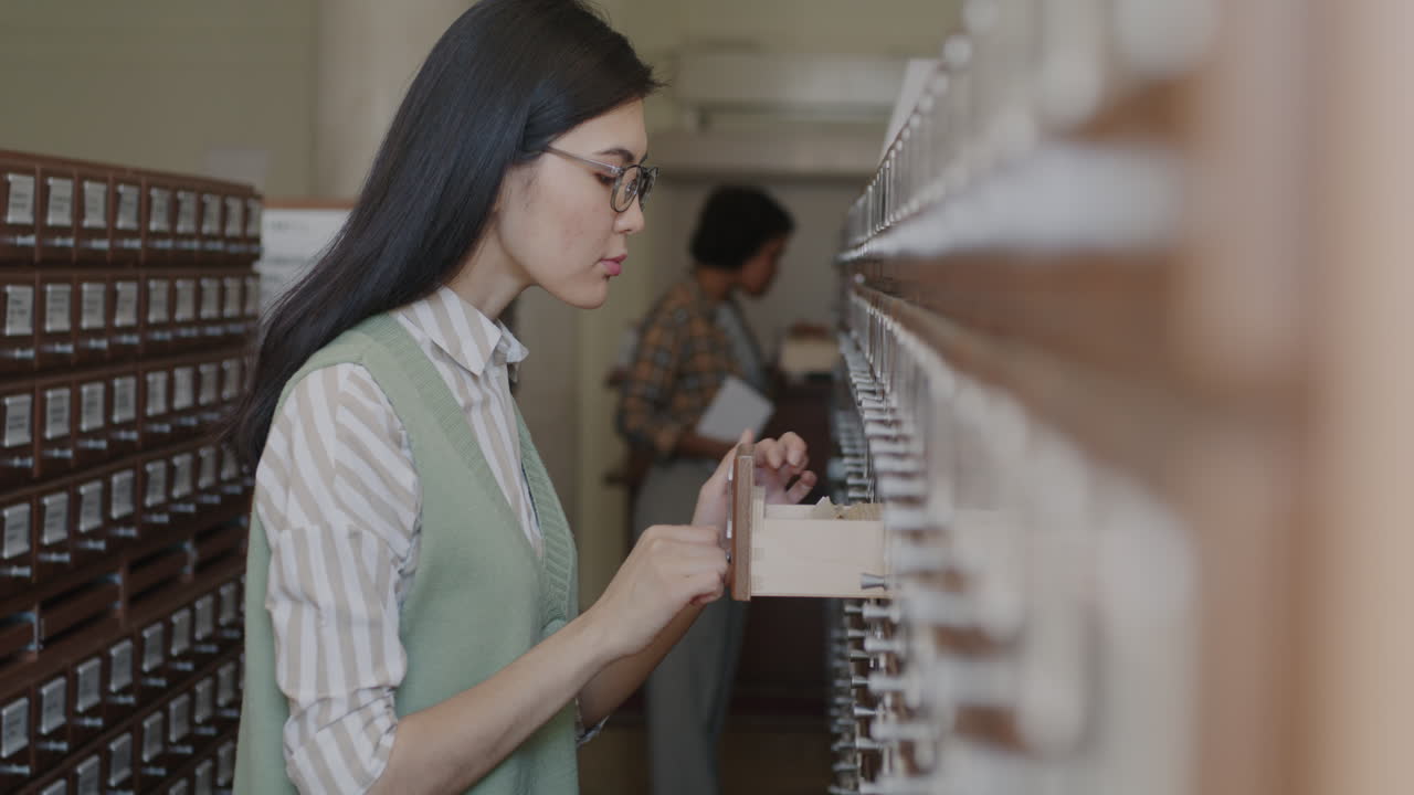 Woman looking for file in a library drawer