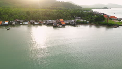Golden-hour-sunrise-rays-spread-across-Koh-Lanta-coastal-old-town,-aerial-reveal
