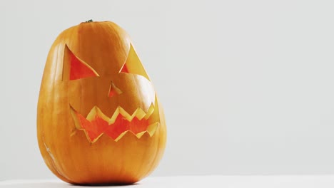 Close-up-view-of-scary-face-carved-halloween-pumpkin-against-grey-background