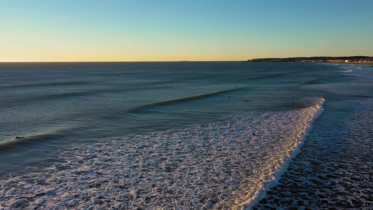 imágenes aéreas estacionarias de olas que se dirigen a la orilla mientras 4 surfistas esperan y una gaviota vuela hacia la orilla en una fría mañana de diciembre en york beach maine