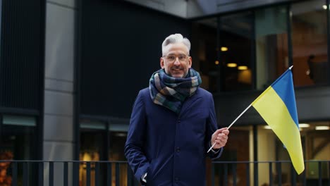 man holding ukrainian flag in urban setting