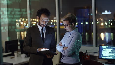dos compañeros de trabajo en la oficina usando una tableta y resolviendo el ataque de hackers en su empresa