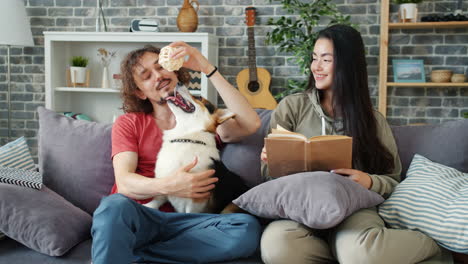 couple and corgi relaxing on a couch