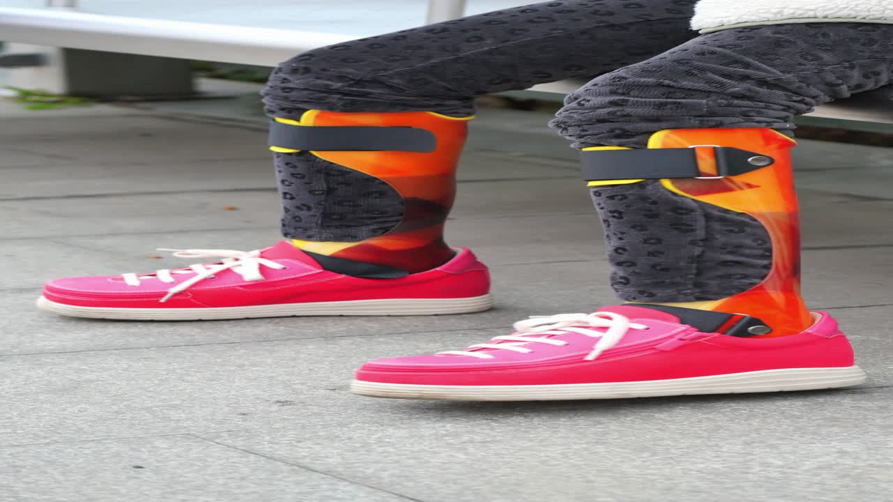 niño con soporte para las piernas y zapatos rosados