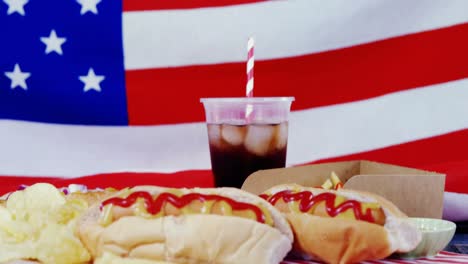 perrito caliente y bebida fría servida contra la bandera estadounidense