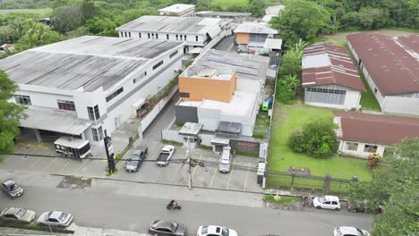 aerial drone shot : a sprawling warehouse with cars coming and going, forklifts moving goods, people at work