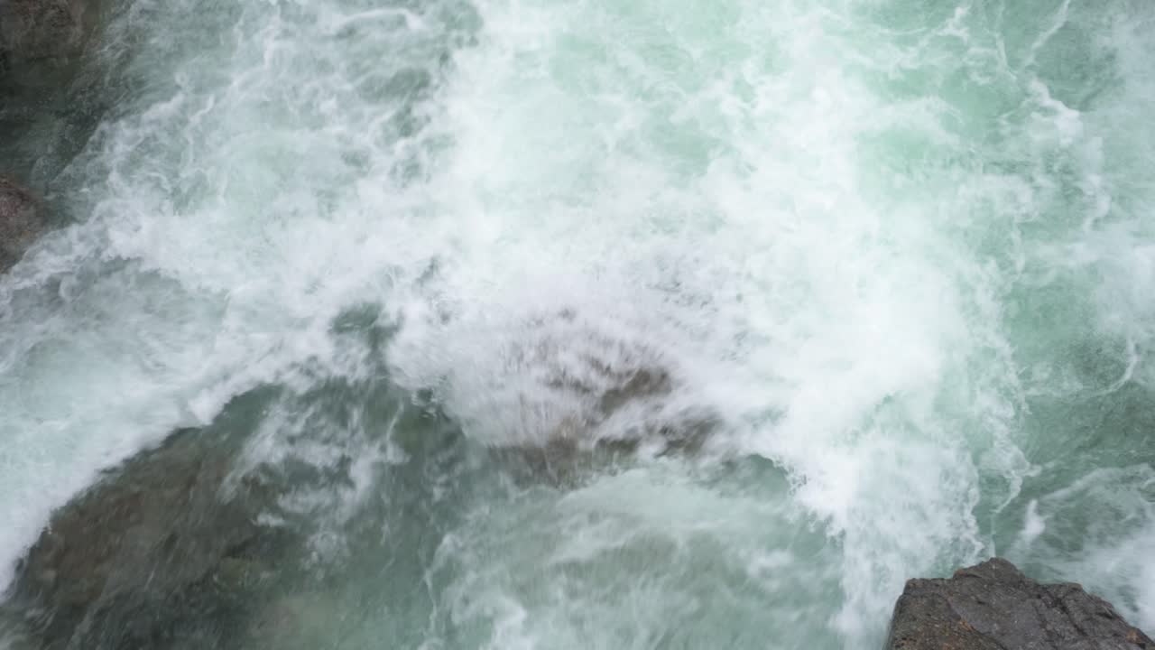 Strong river rapids flowing over rocks, glacier meltwater, aerial top down