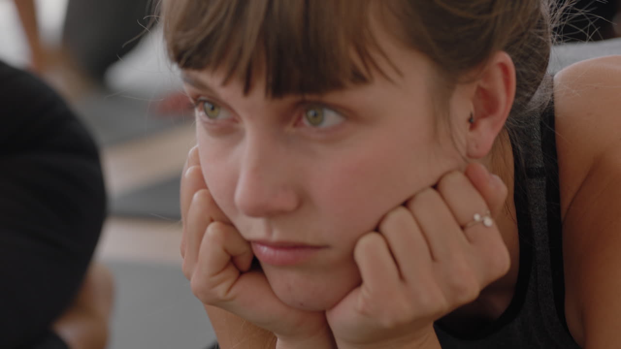 retrato de una mujer de yoga aburrida en clase de fitness relajándose en una colchoneta de ejercicios con aspecto pensativo