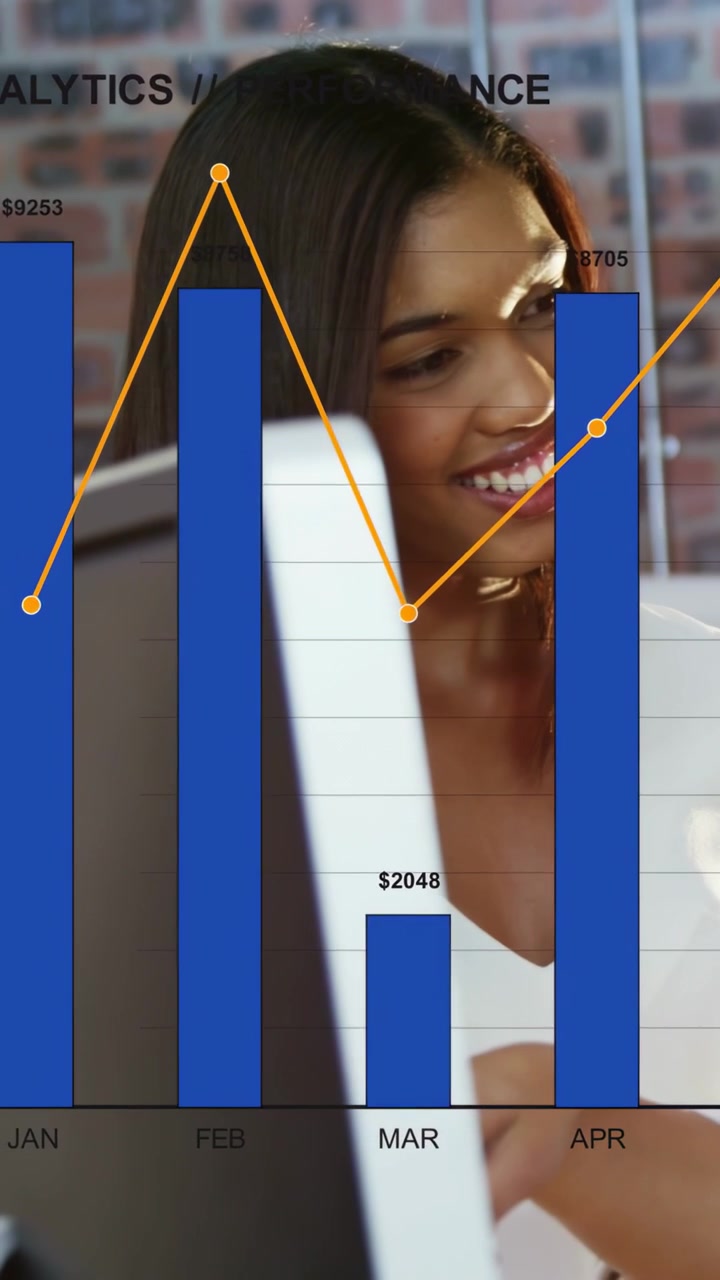 Vidéo verticale : Femme pointant un écran sur un bureau, lançant des graphiques financiers révélant les revenus mensuels.