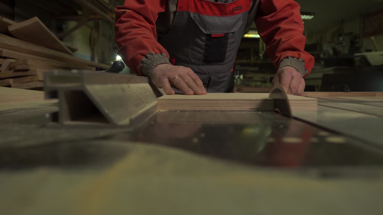 плотник, рабочий режет деревянную доску круговой пилой на рабочем столе