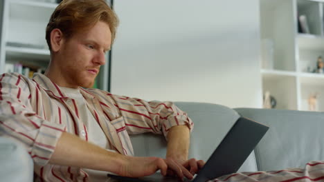 Busy-freelancer-typing-computer-closeup.-Ginger-guy-browsing-web-in-living-room