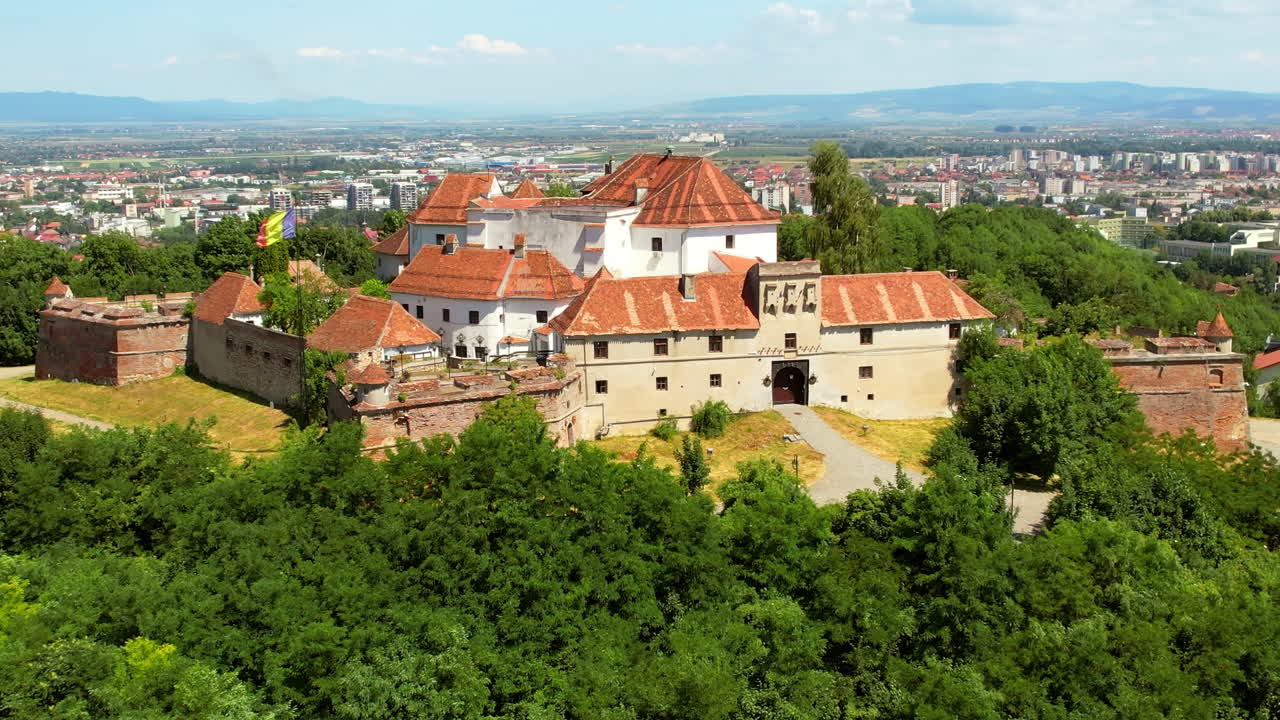 Aerial drone view of The Citadel in Brasov, Romania. Medieval fortress on the top of a hill. Buildings, green trees