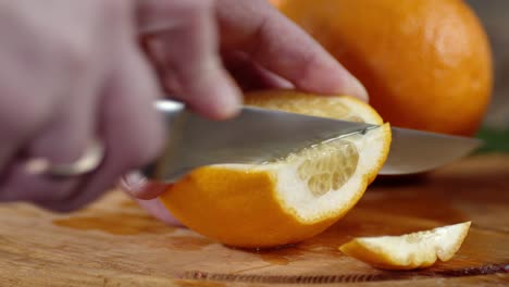 men hands cut ripe orange into pieces.