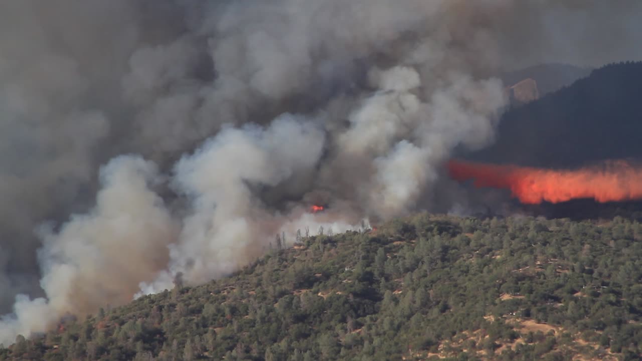 Aereo che rilascia ritardante su un furioso incendio boschivo in California.