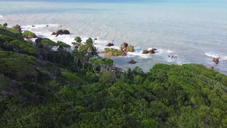 oceanside pan shot down tropical mountain casting out to beautiful tourist beaches