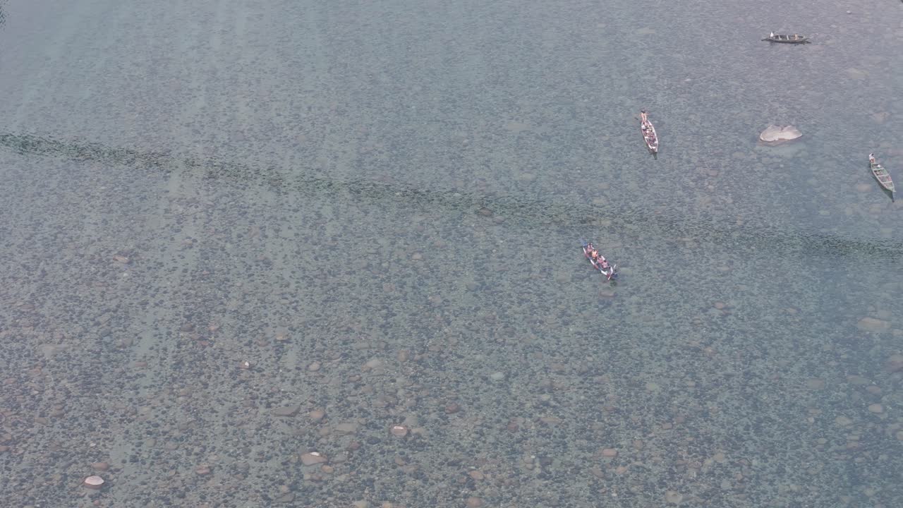 Top-down aerial view of the crystal-clear water of the Umngot River in Shnongpdeng, Meghalaya, revealing the pebble riverbed