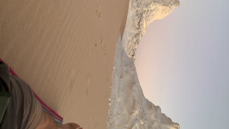 vertical of caucasian tourist resting and relaxing in front of scenic sculpture of white desert