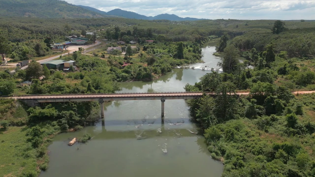 Piccolo villaggio tranquillo nel Vietnam rurale, ponte che attraversa il fiume, drone si muove a sinistra, vista dall'alto 4K 30FPS.