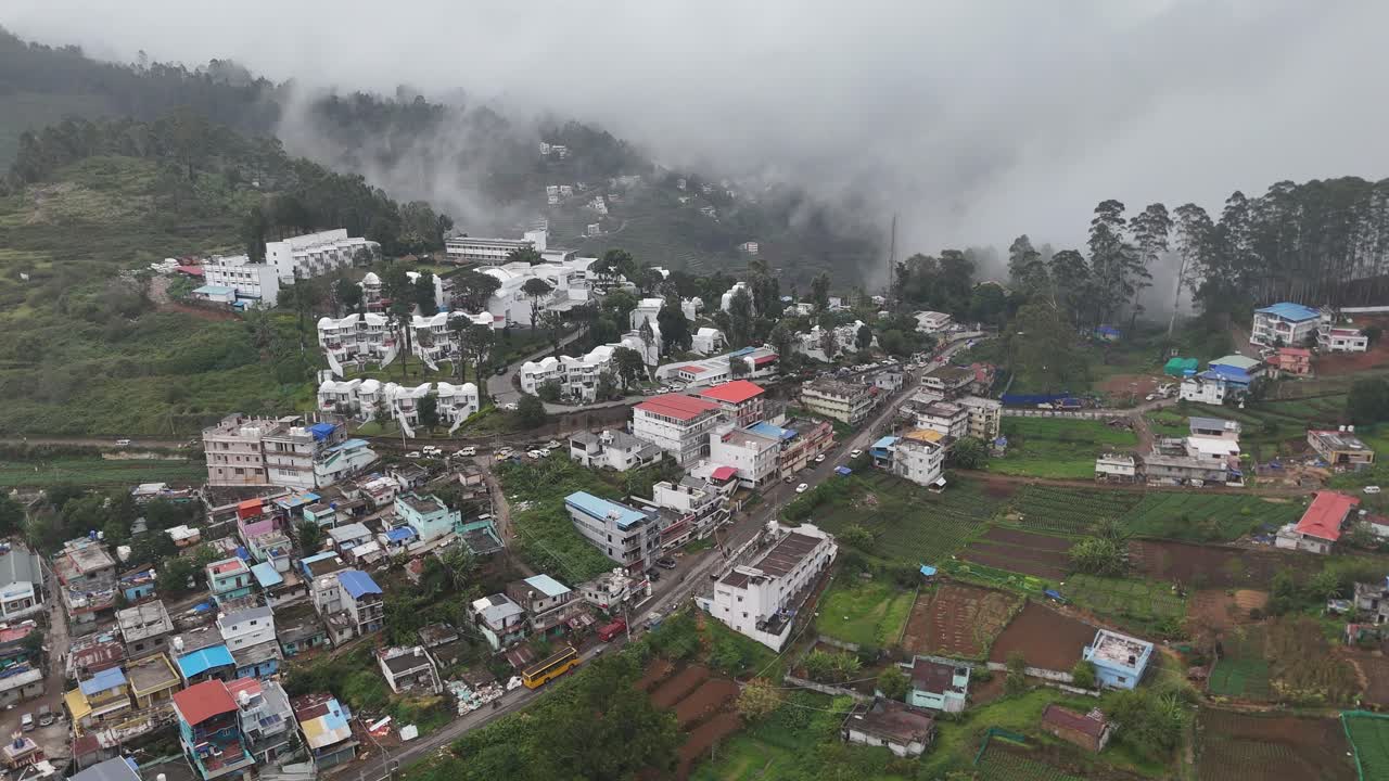 Aerial sweep capturing a serene hill town surrounded by dense green forests