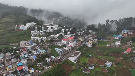 Aerial sweep capturing a serene hill town surrounded by dense green forests