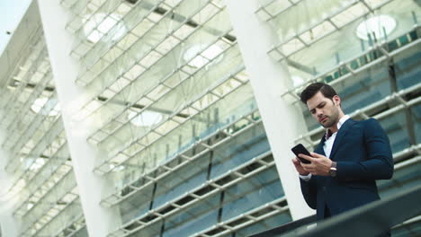 handsome businessman using smartphone near stadium