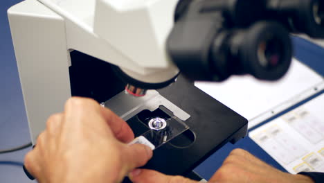 A-scientist-preparing-a-slide-of-cancer-cells-from-a-medical-biopsy-with-a-microscope-in-a-medical-research-science-lab