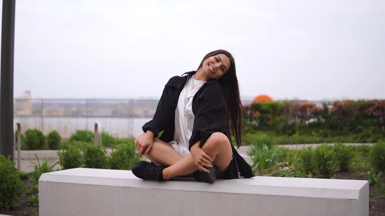 joven modelo con hermoso espíritu vibras positivas sentado en un banco en posición de meditación de siete puntos relajante disfrutando de la vida feliz influenciador de altas vibraciones instagram ojos grandes nublado cámara lenta